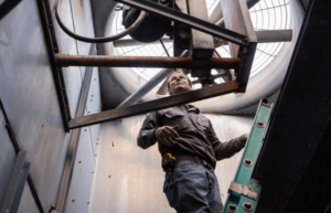Man climbing up ladder in an HVAC duct 