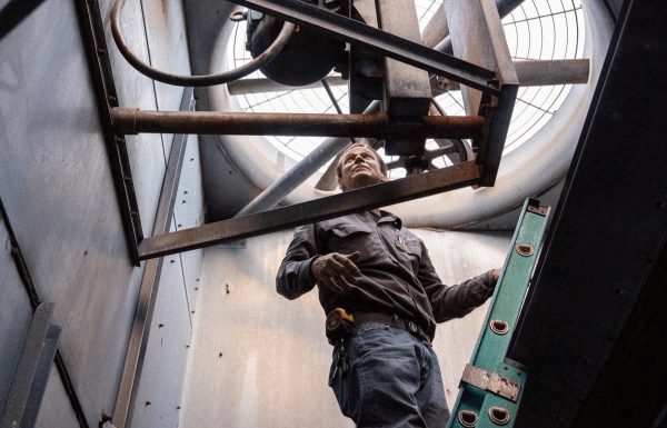 Man climbing up ladder in an HVAC duct