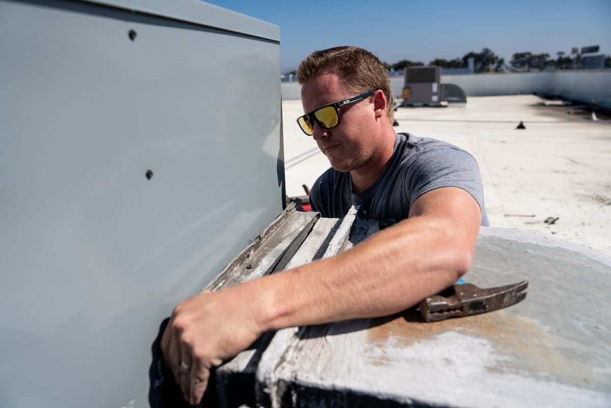 Man working on hvac unit on top of a building