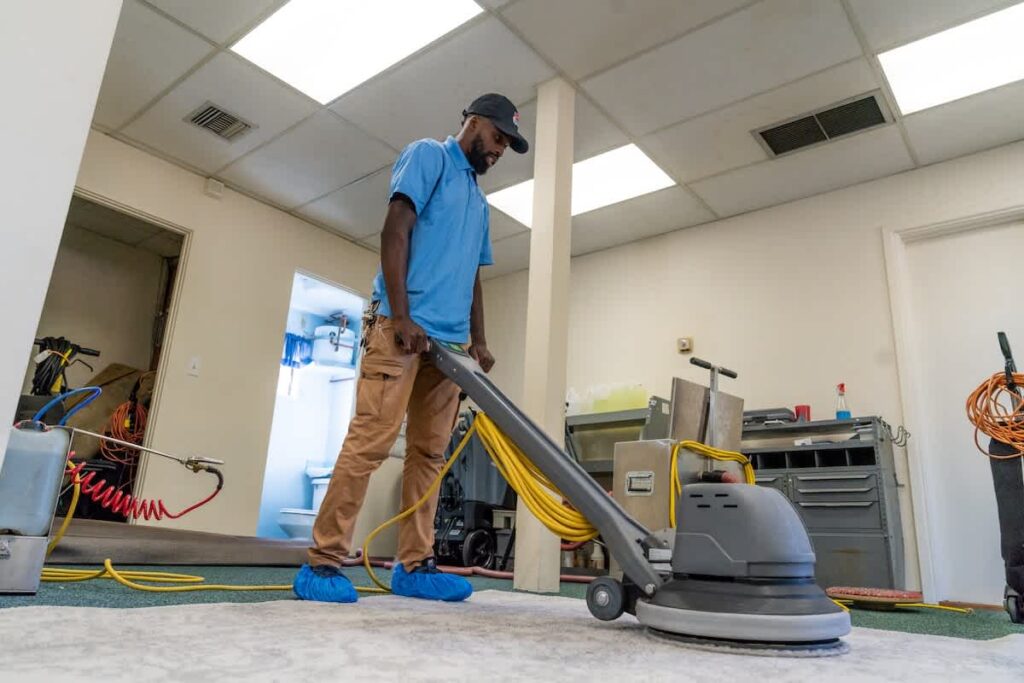 Man cleaning carpet with machine