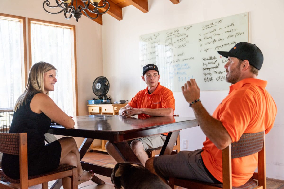 - Housecall Pro two pros sitting at a table with a customer