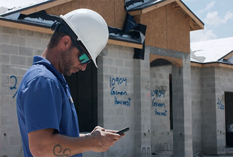 - construction worker in hardhat using phone at job site