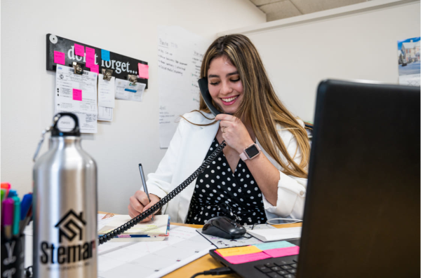 Woman taking notes while answering office phone