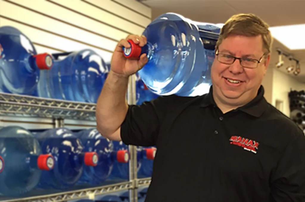 Alex G. owner of Manax Plumbing carrying 5 gallon water jug on shoulder
