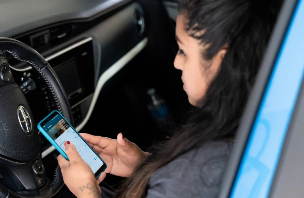 Lilian inside her car checking her mobile phone