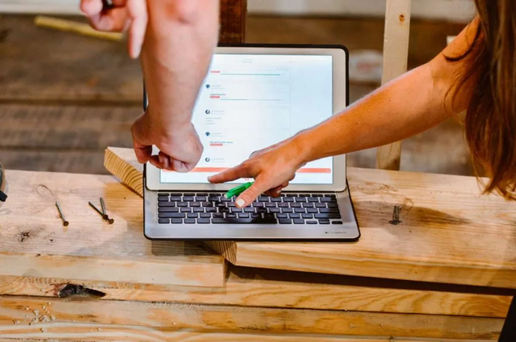 Two pros pointing at laptop on top of wood at construction site