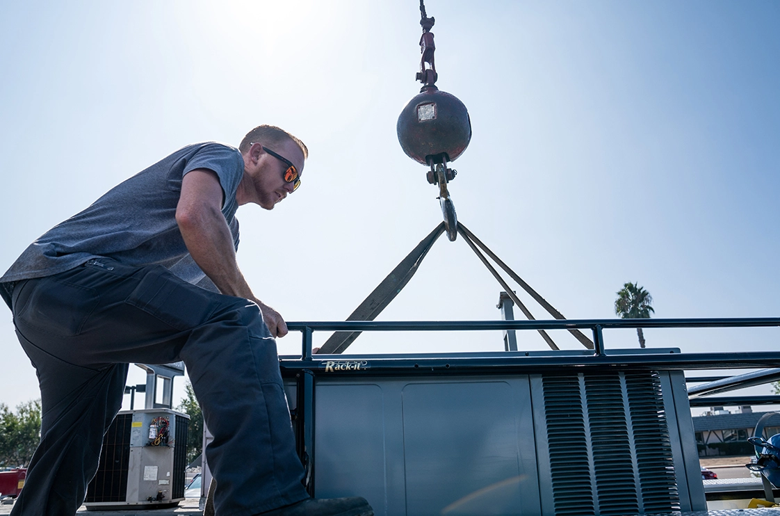 HVAC pro helps set large AC unit with crane