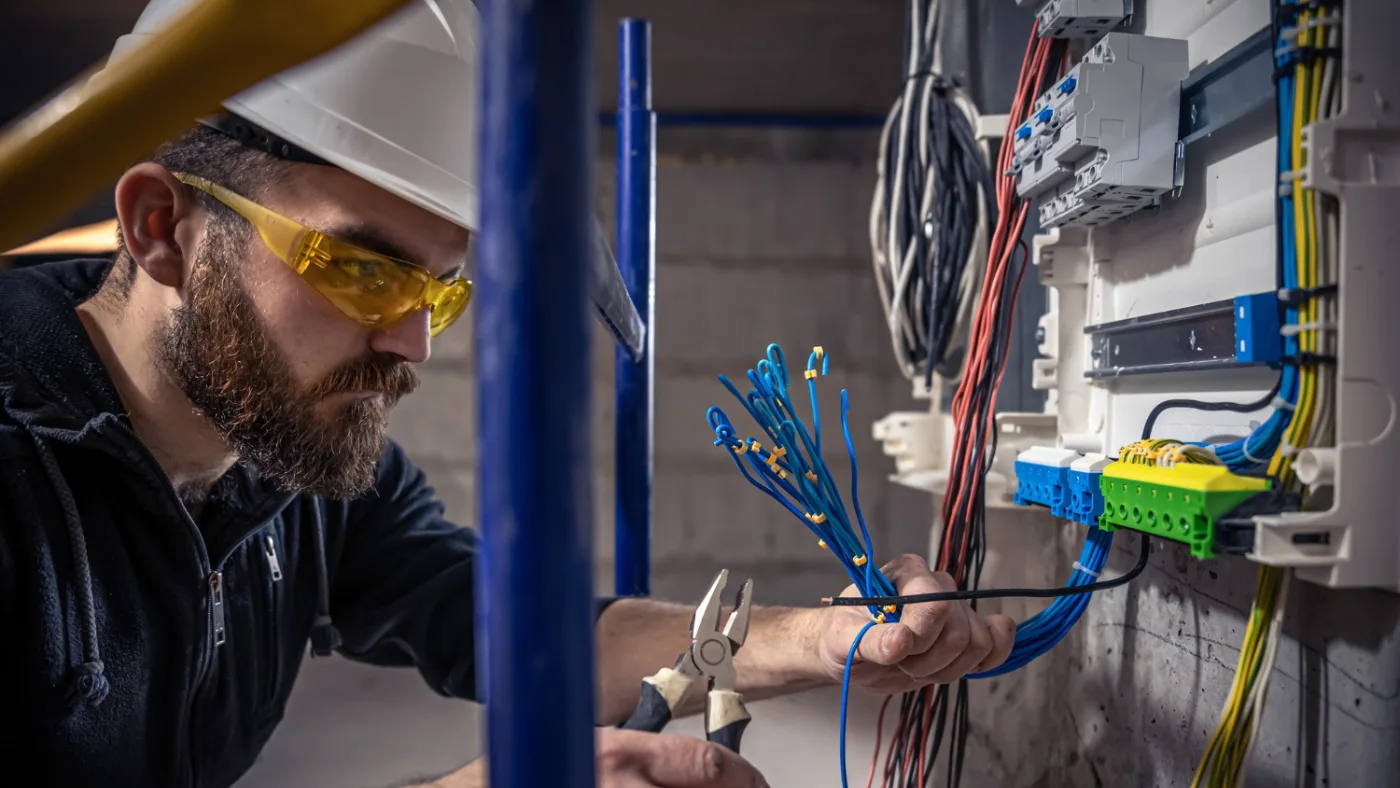 electrician pro works in a switchboard with an electrical connecting cable