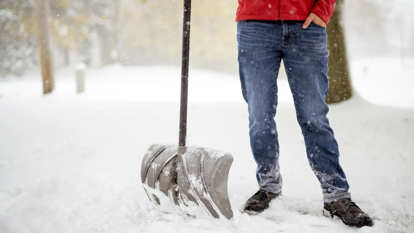 Pro standing on a snowy field and holding a snow shovel