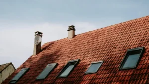 Red tiled roof with skylights and chimney under clear sky
