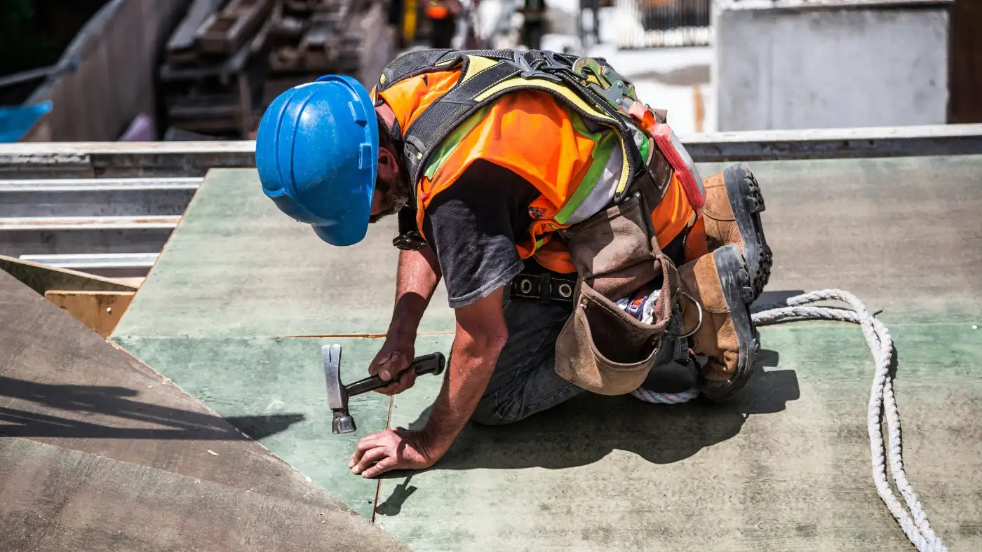 Professional worker on a roof using a hammer