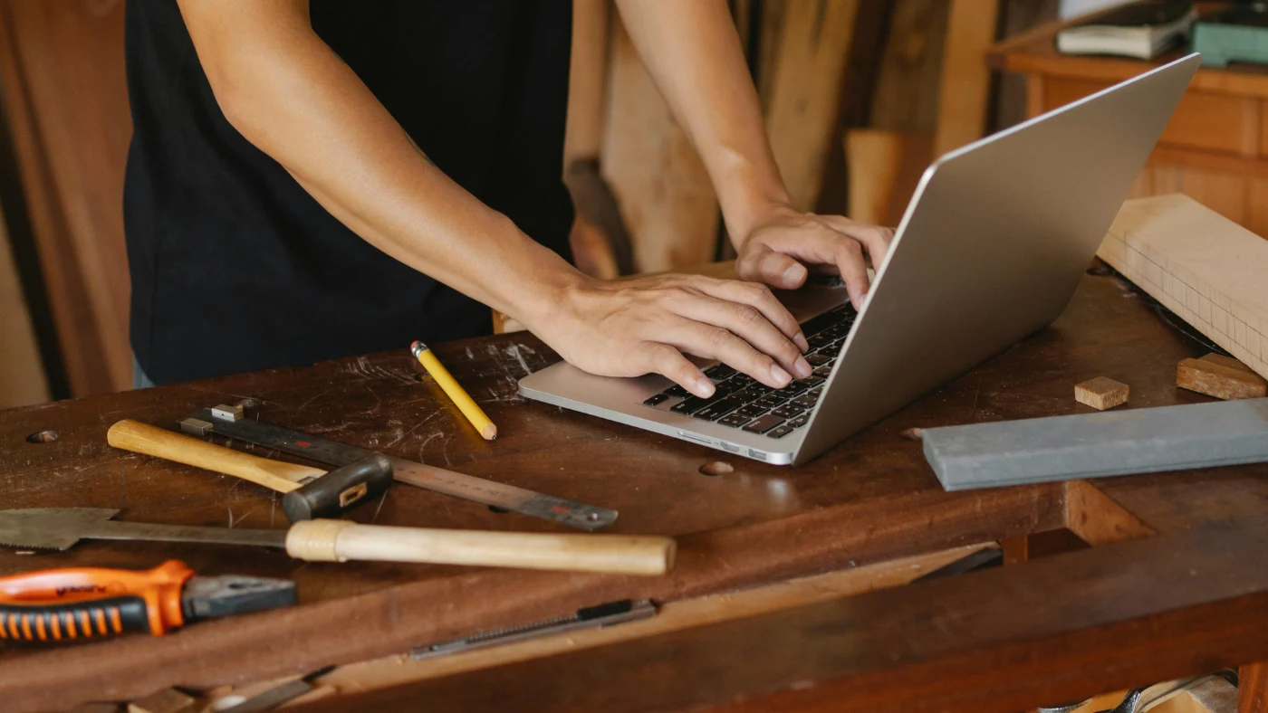 man standing in his workshop and using laptop on a table