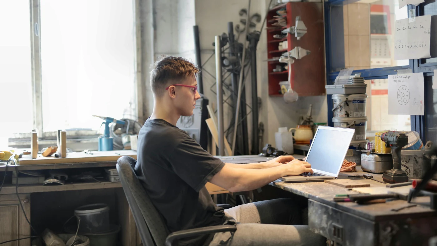 man working on laptop in his workshop