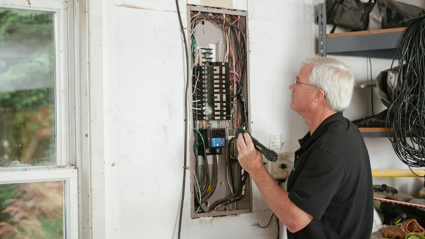 Home service professional inspecting electrical panel, representing modern tools and technology in field service work