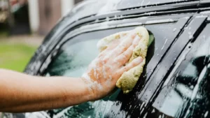 man holding a sponge and washing his car
