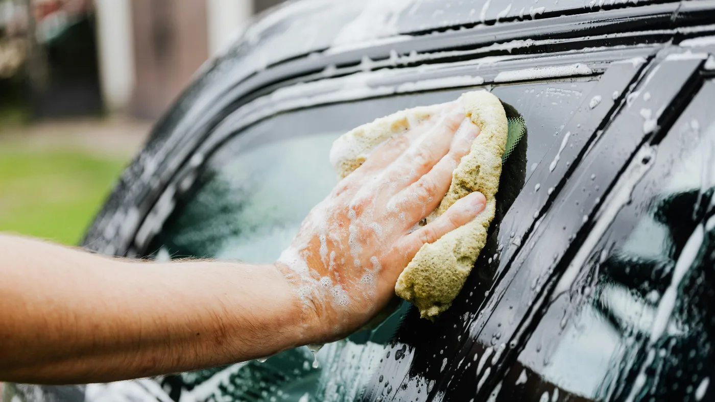 man holding a sponge and washing his car