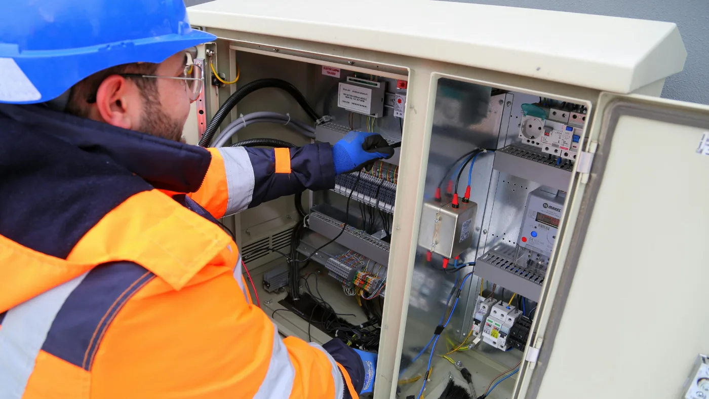 Electrician inspecting electrical control panel inside commercial power cabinet