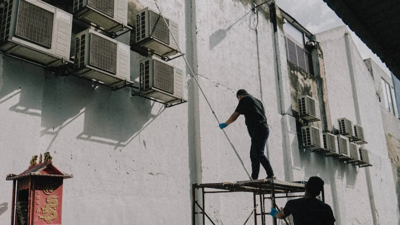 HVAC technicians servicing exterior air conditioning units on commercial building