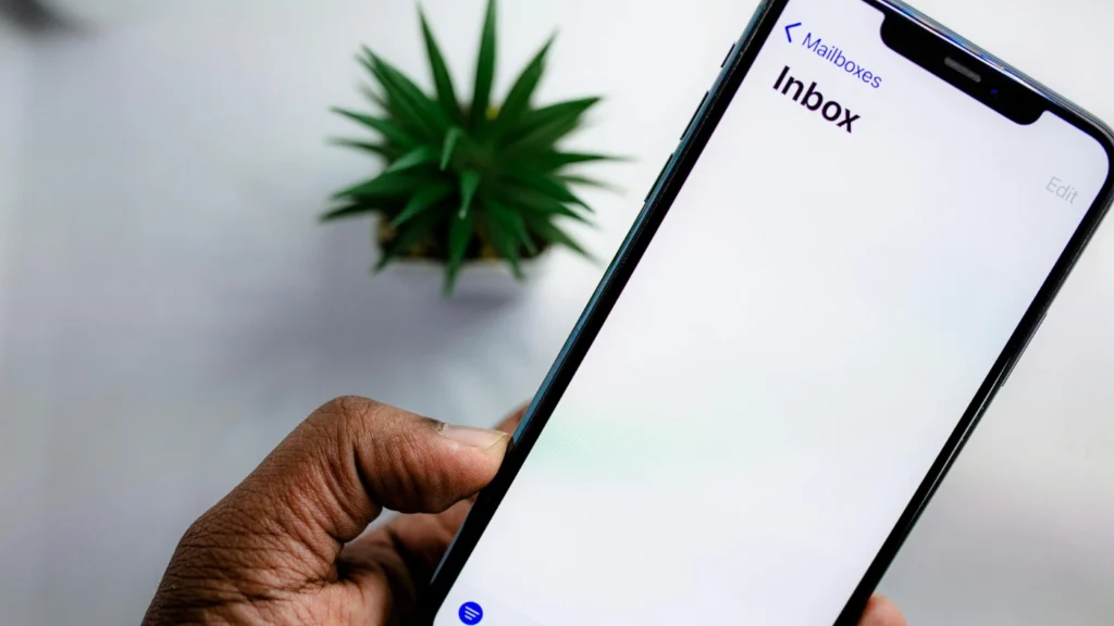 Man holding a smartphone with the inbox open on the screen