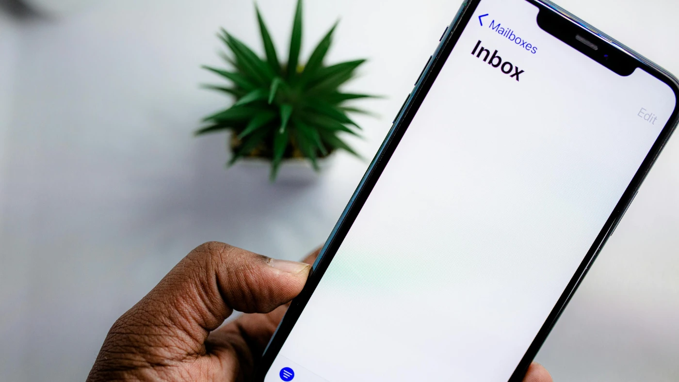 Man holding a smartphone with the inbox open on the screen