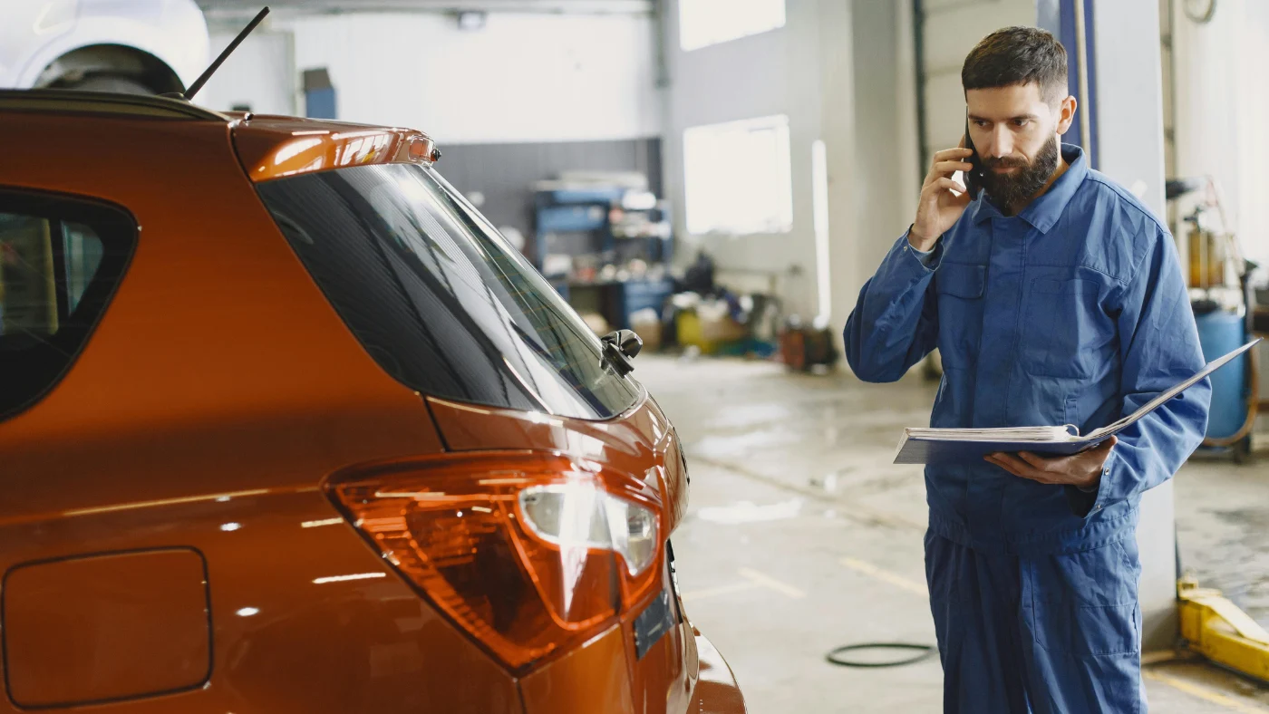 Man standing, holding a file, and talking on a phone held to his ear