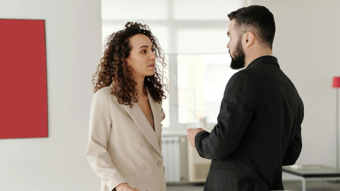 Two professionals having a conversation in an office.