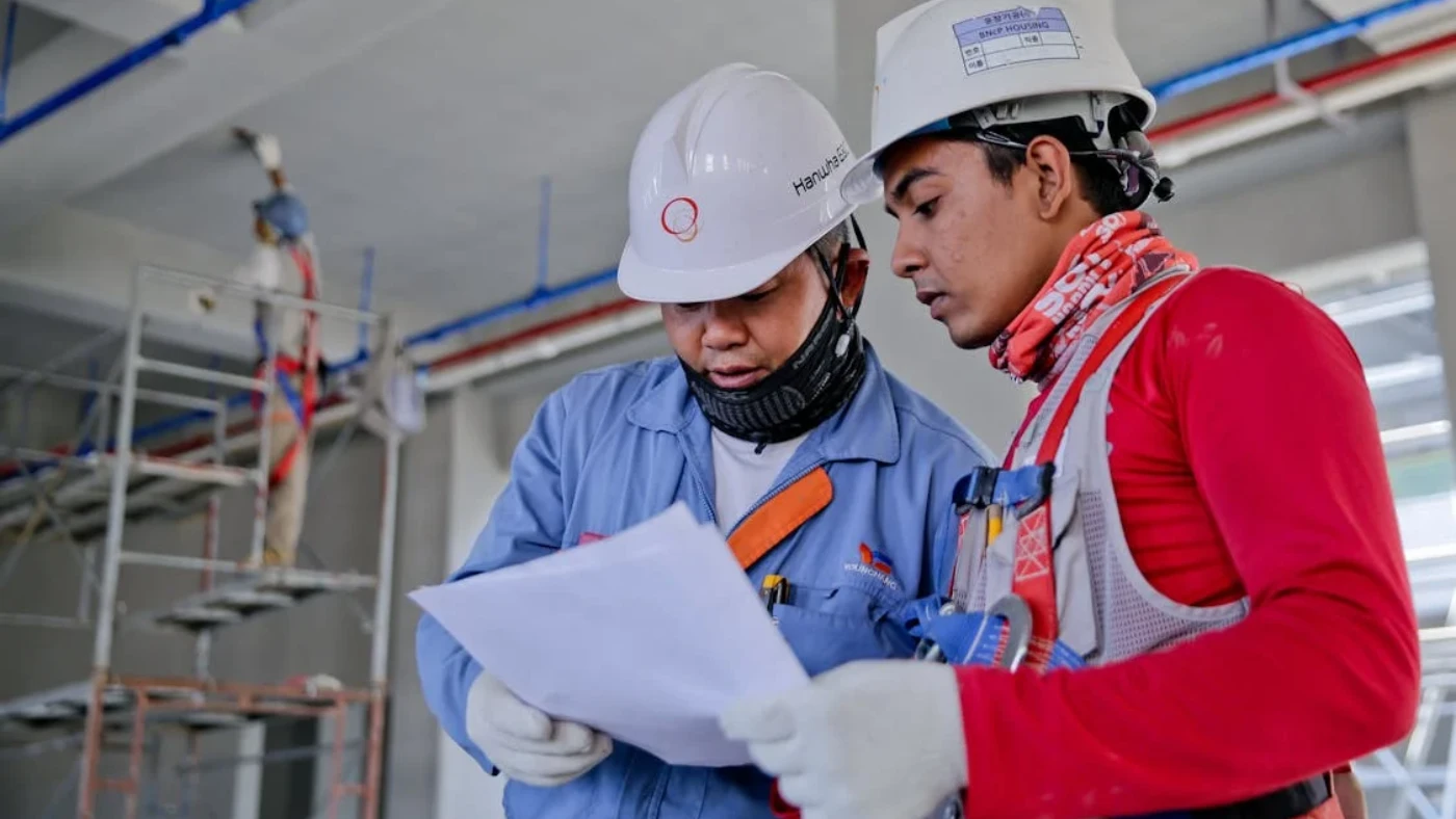 Two electrical contractors reviewing plans at a construction site