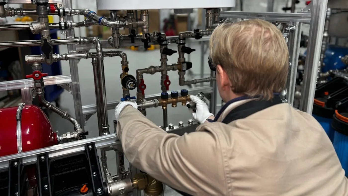 Plumber installing and adjusting residential water heating and pipe system