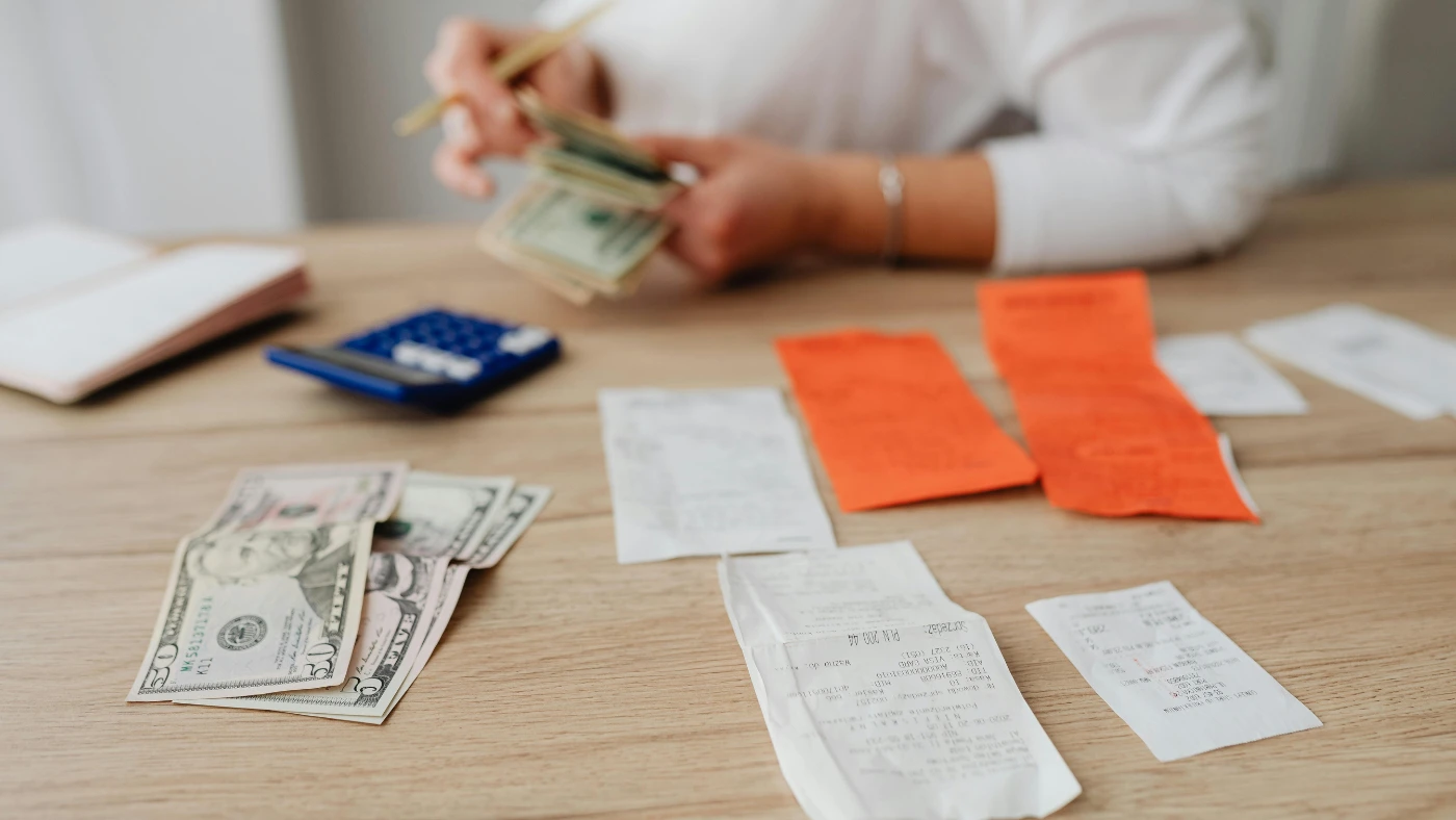 Person organizing cash and receipts to track business expenses