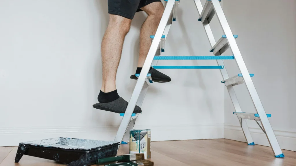 Man standing on a ladder painting a wall