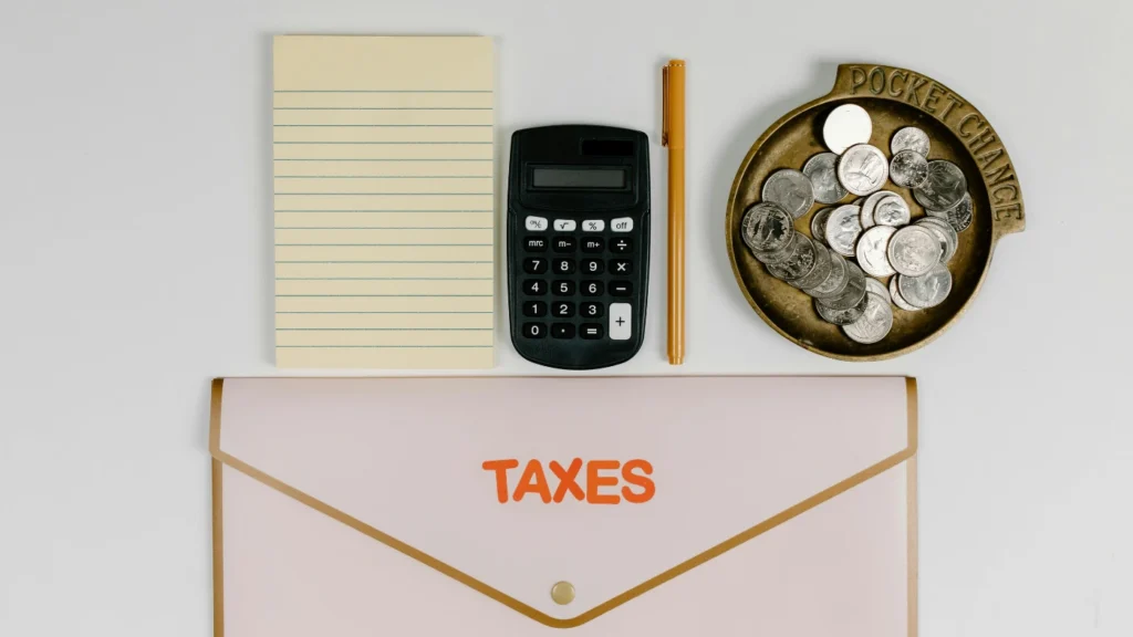 Taxes envelope with calculator, notepad, and coins on desk