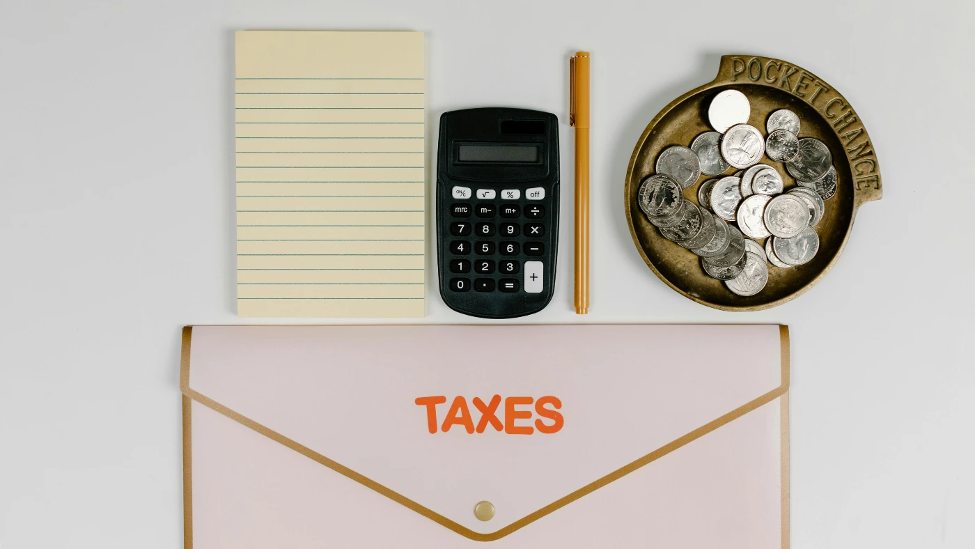 Taxes envelope with calculator, notepad, and coins on desk