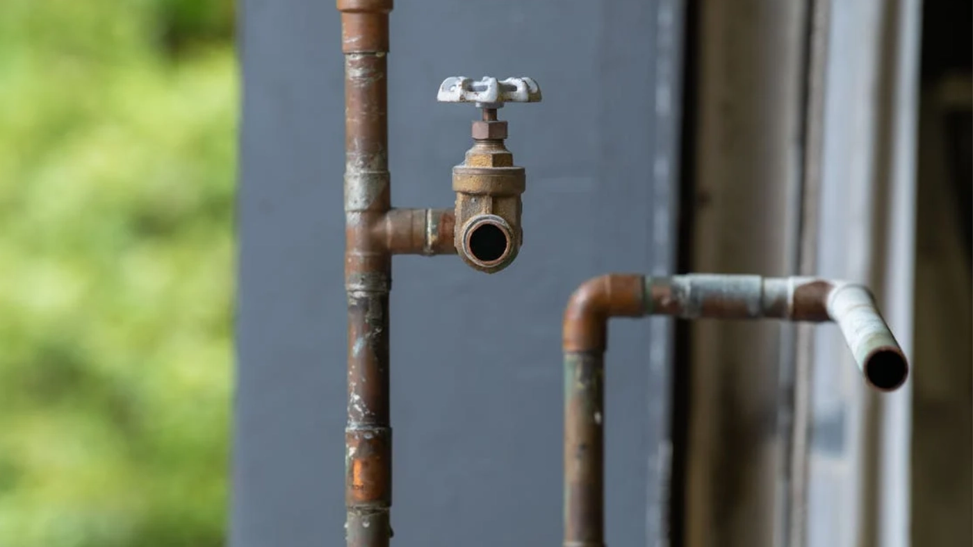 Exposed copper plumbing pipes with shut-off valve and open pipe connection