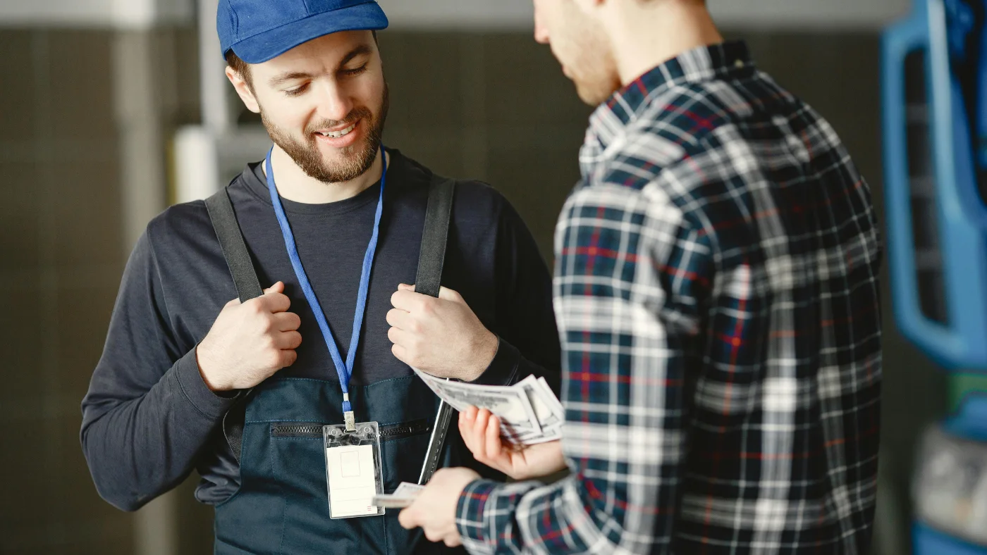Customer paying a worker in uniform with cash.