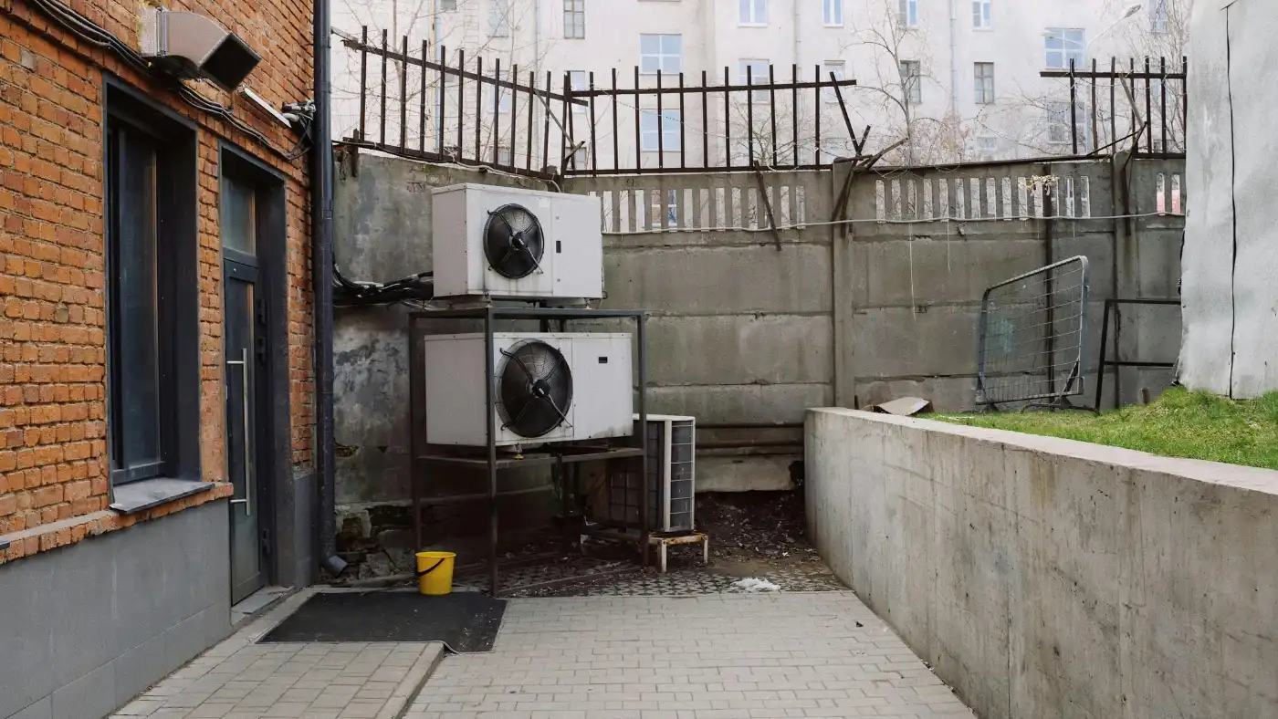 Outdoor HVAC condenser units installed beside a commercial building in an urban area