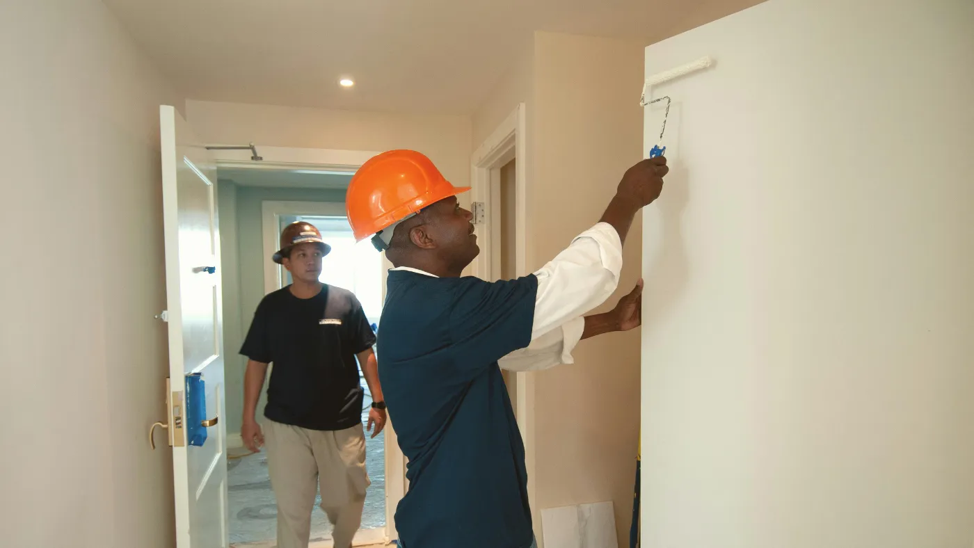 Professional painter applying fresh white paint to an interior wall with a roller