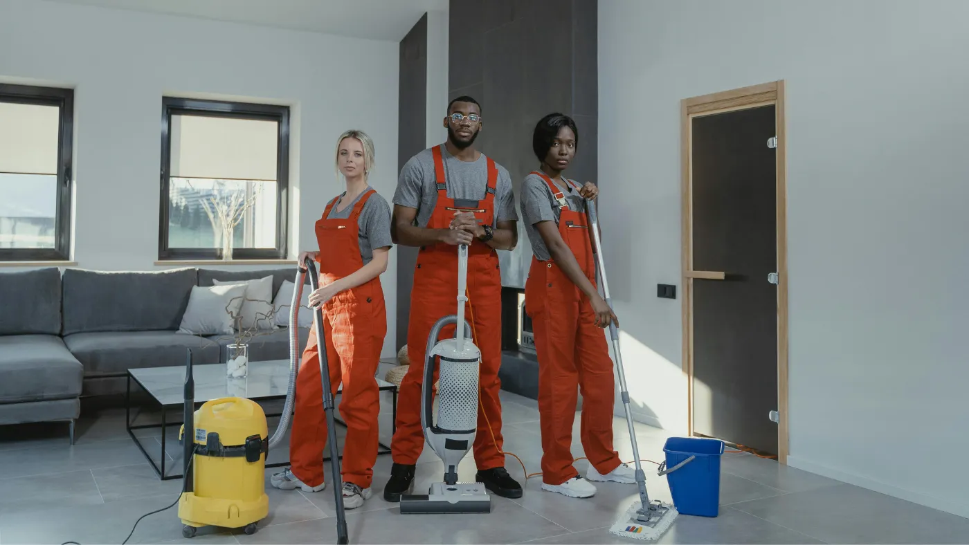 Professional cleaning team posing with vacuum and floor cleaning equipment in a home