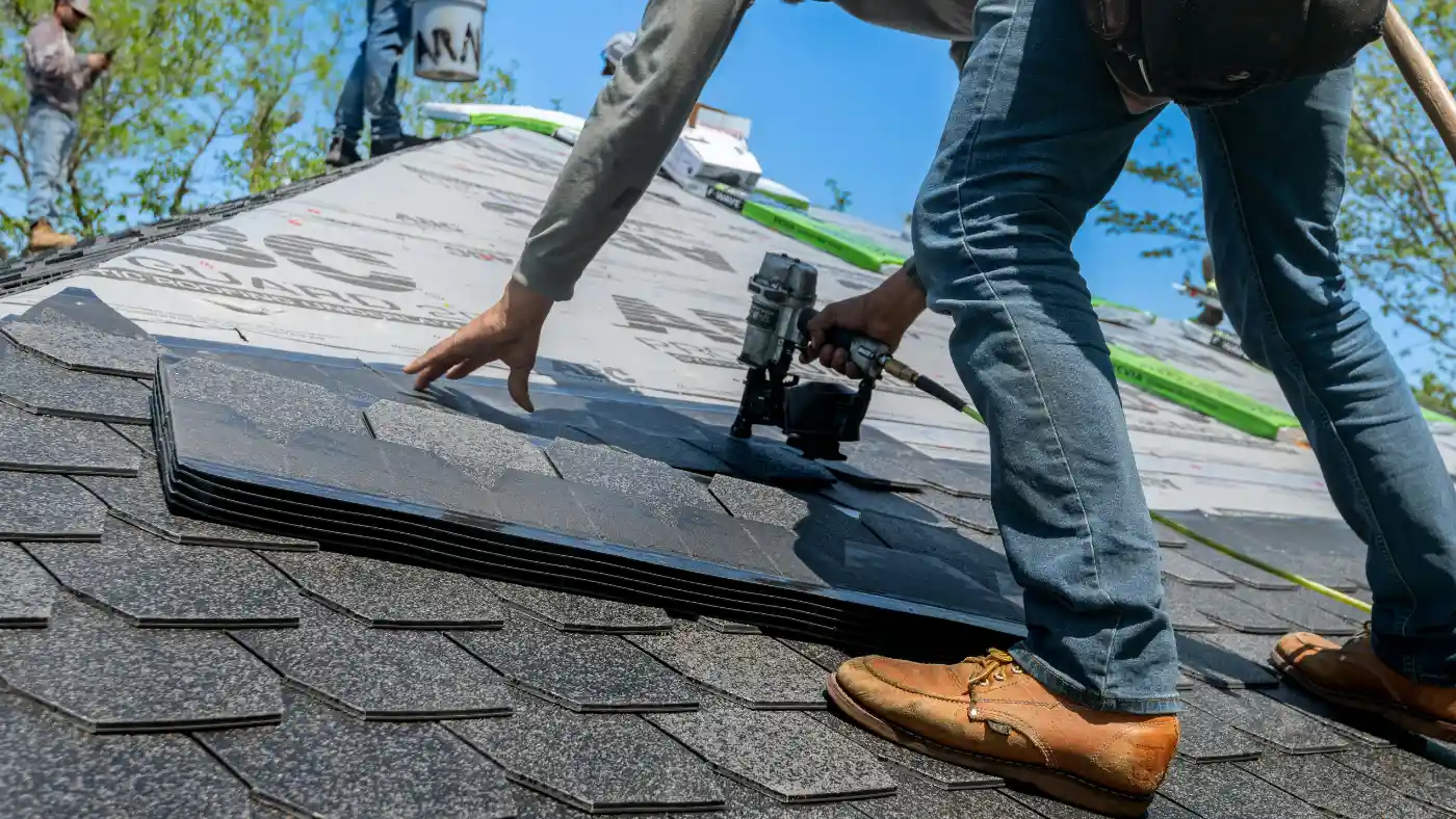 Roofing contractor installing asphalt shingles on a residential roof