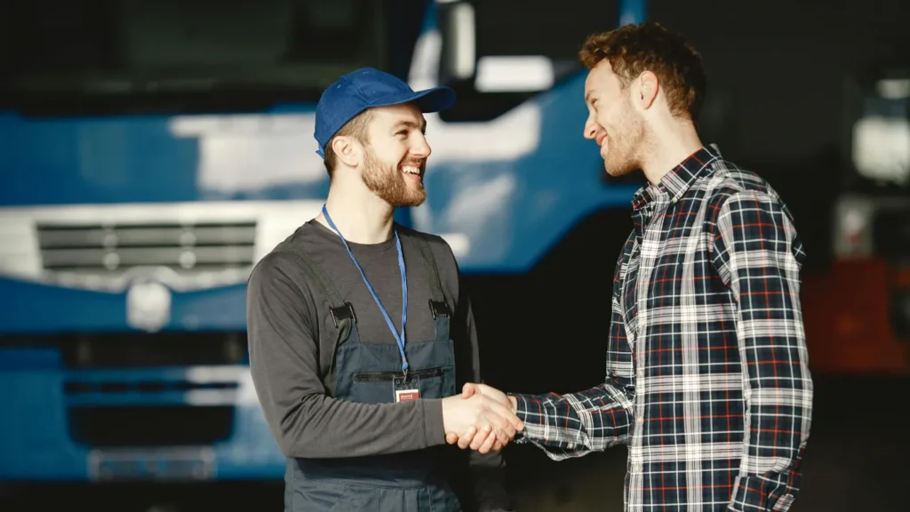 Service technician shaking hands with a customer in a commercial garage
