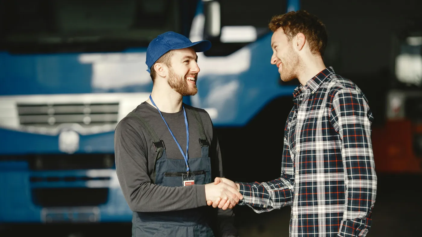 Service technician shaking hands with a customer in a commercial garage