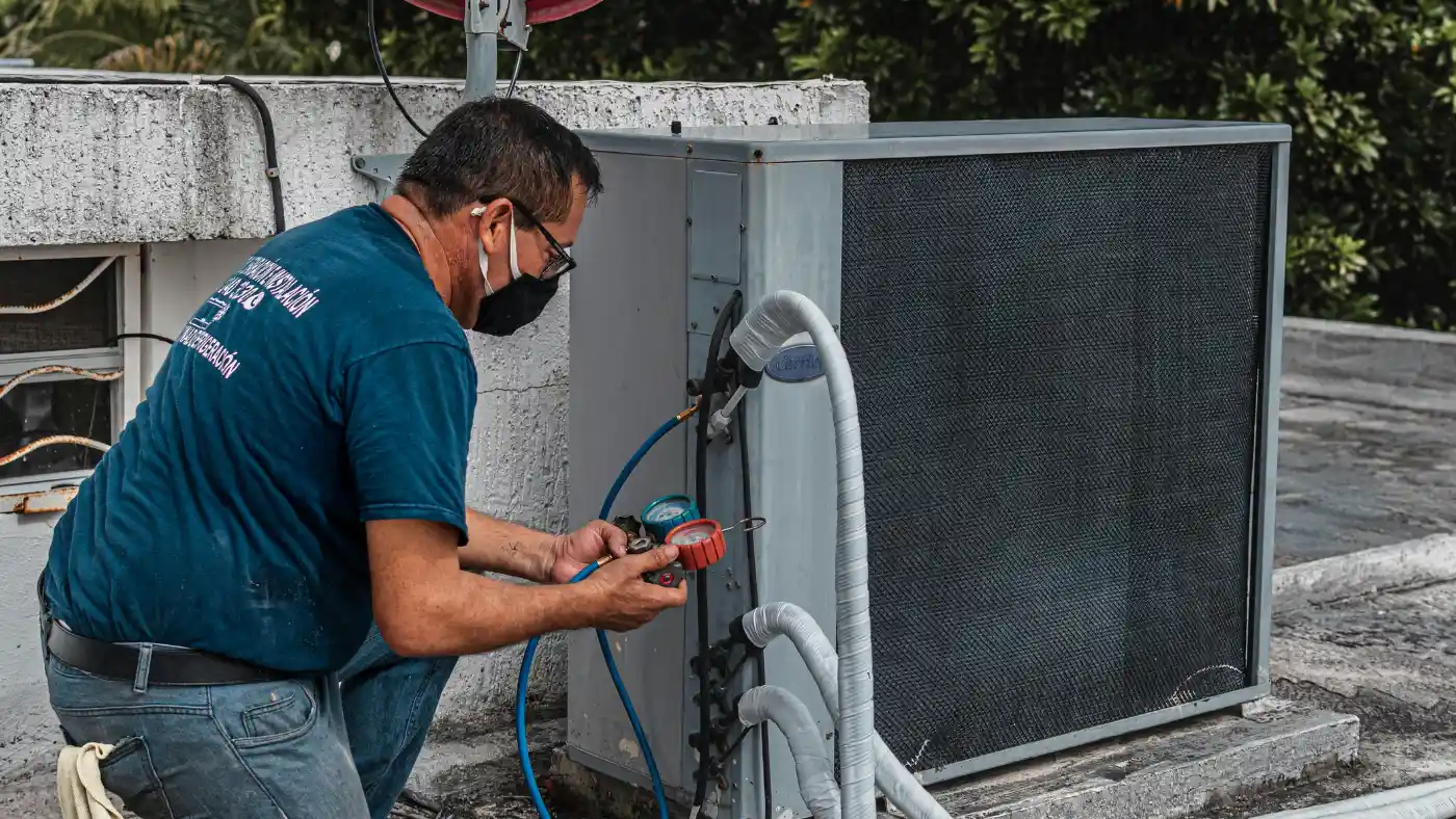 HVAC technician checking refrigerant pressure on a rooftop air conditioning unit