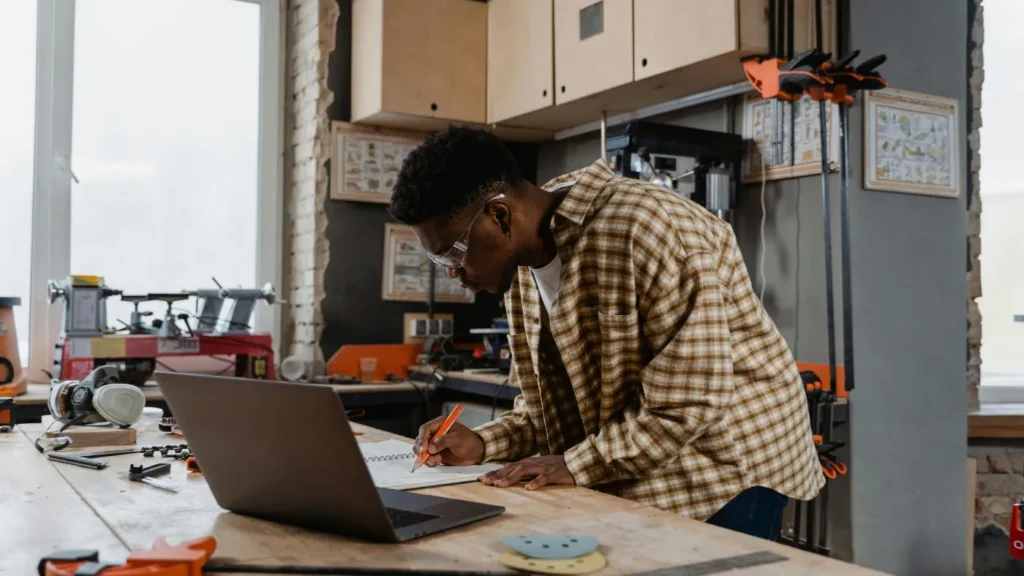 HVAC contractor working on a website plan at a workbench with a laptop in a workshop
