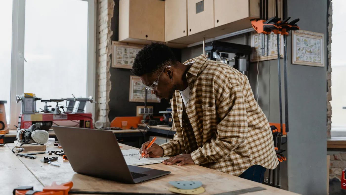 HVAC contractor working on a website plan at a workbench with a laptop in a workshop
