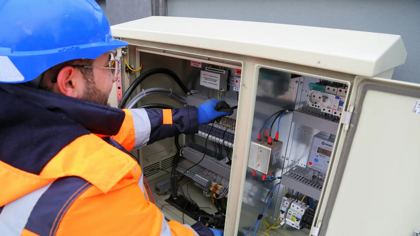 electrician repairing a fuse box, checking wiring and electrical connections.