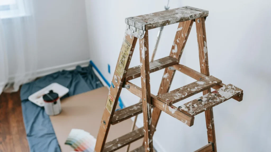 Paint-splattered step ladder in room prepped for interior painting