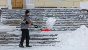 Snow removal worker shoveling snow from outdoor steps in winter