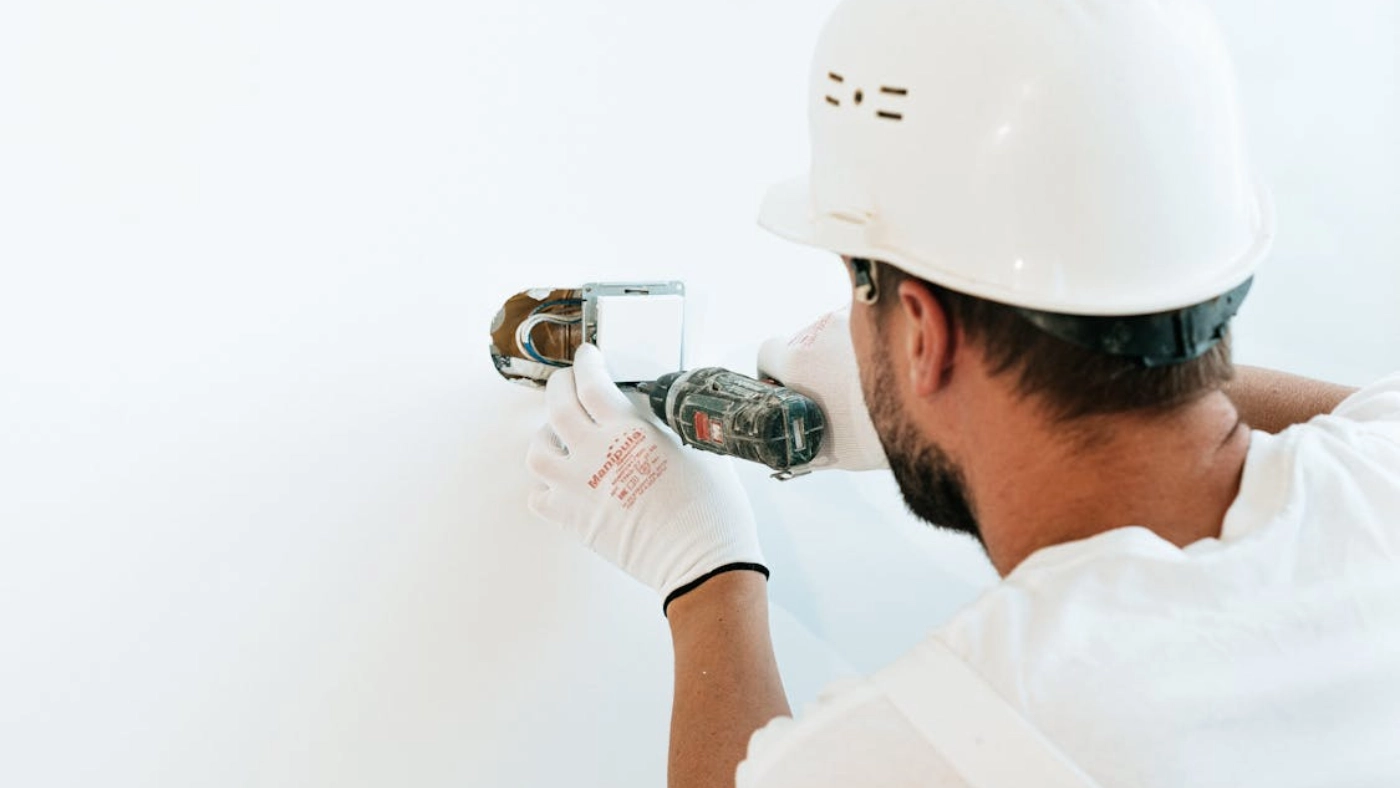 Electrician installing wall outlet with drill for electrical service marketing