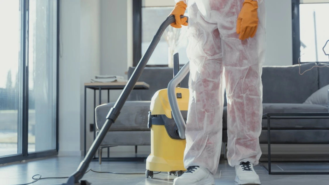 Crime scene cleaner in protective suit vacuuming floor, representing cleaning work and job duties