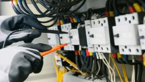Electrician testing circuit breakers inside electrical panel with multimeter probes
