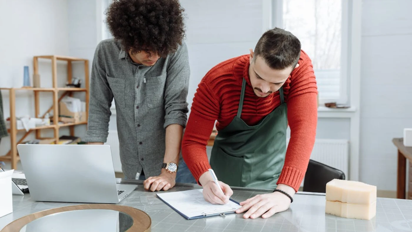 Small business owners reviewing documents and signing paperwork related to business insurance coverage and costs